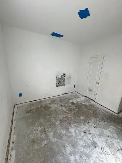 Empty room with the flooring removed to bare slab and tape marking moisture readings near Prosper, TX