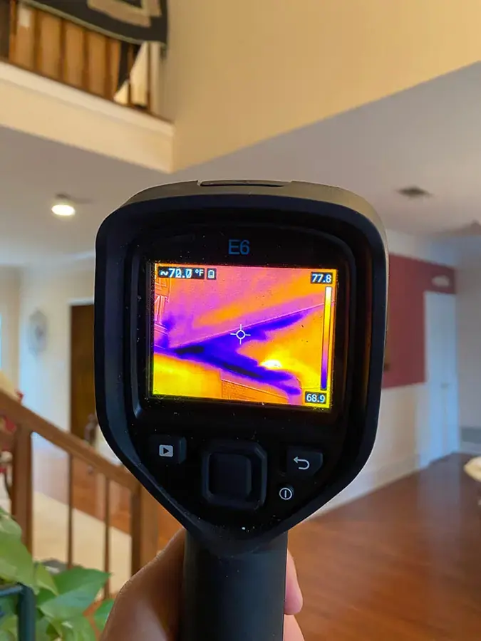A thermal imaging camera held up in a two-story home to look for moisture behind walls and ceilings