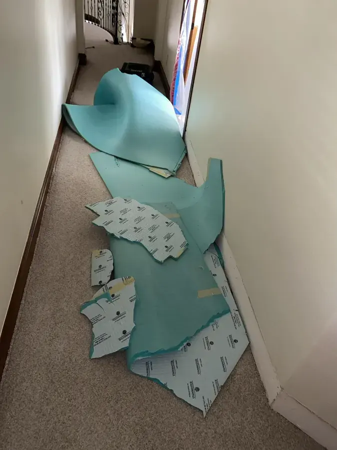 Wet carpet pad pulled up along a hallway and left in a pile to be discarded